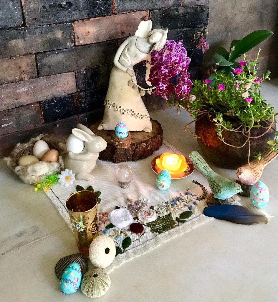 Altar com representação de Ostara no centro, ovinhos, coelhos, passaros.